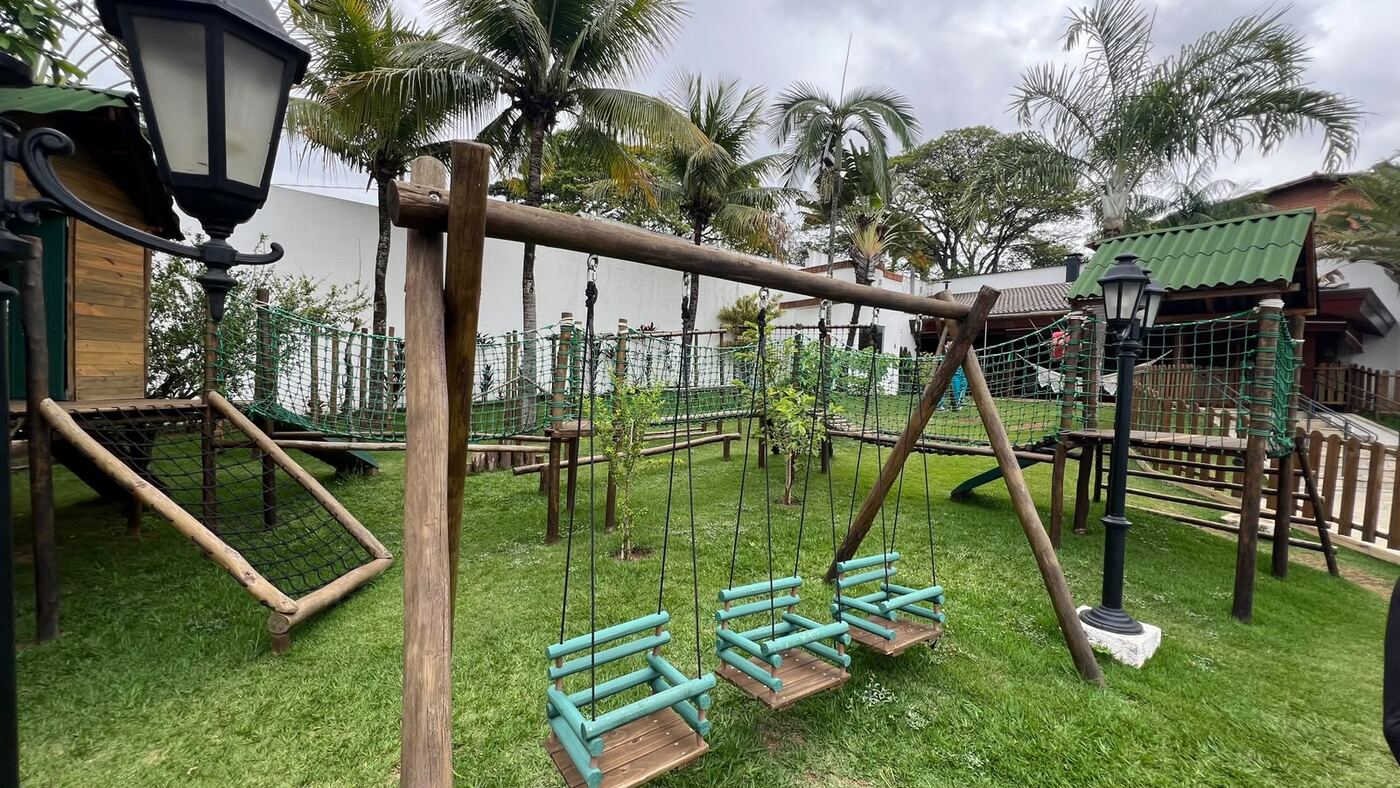 Playground de madeira com balanços, casinha e rede de escalada
